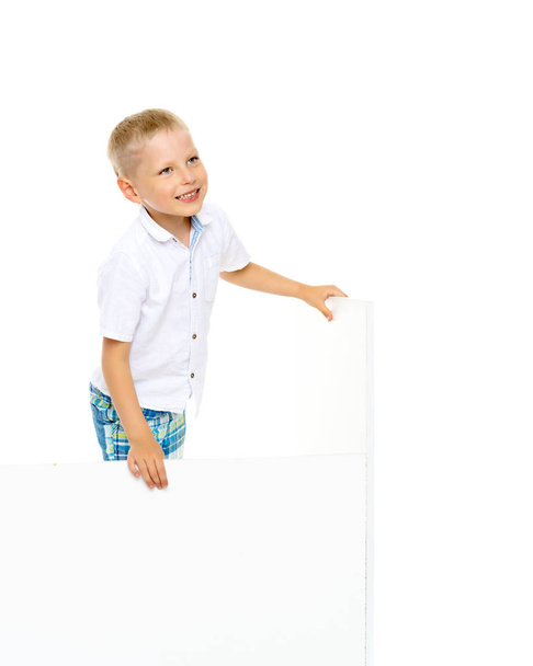 Un petit garçon regarde par derrière une bannière vide. - Photo, image