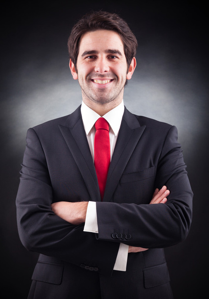 Friendly handsome businessman standing on black background - Fotó, kép