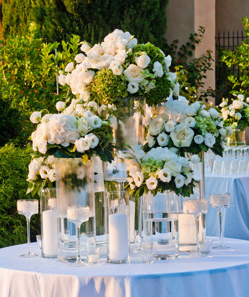 большие цветочные композиции белых роз и гортензий готовы для влюбленных, освещенных теплым светом заката
 - Фото, изображение