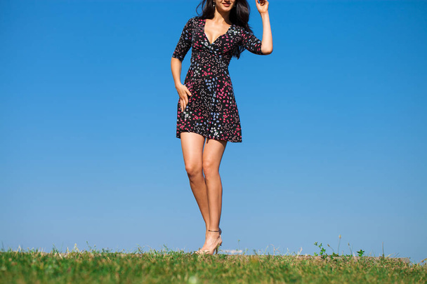 Full body beautiful young brunette woman in summer dress on a summer day, against blue sky  - Фото, зображення
