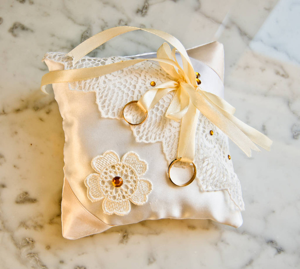 bagues doubles en or sur oreiller en satin blanc doux avec décorations florales faites à la main
 - Photo, image