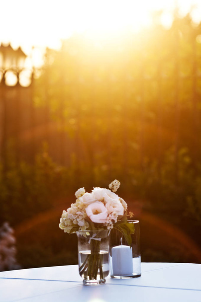 Strauß weißer Rosen und Hortensien bereit für Verliebte, die vom warmen Licht des Sonnenuntergangs erleuchtet werden - Foto, Bild