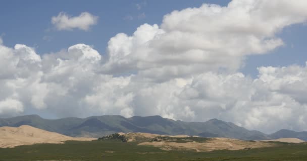4k masa de nubes hinchadas blancas rodando sobre la cima de la montaña y las dunas de arena del desierto
. - Metraje, vídeo