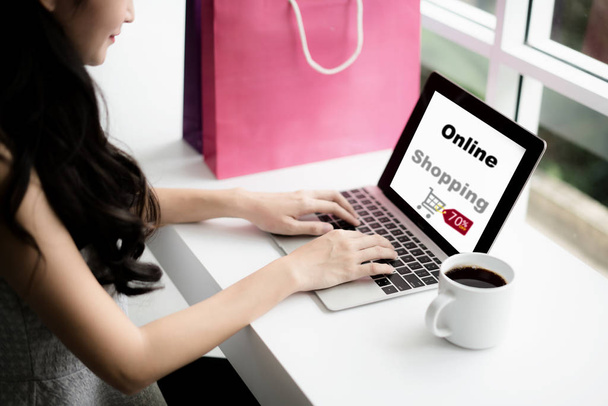 Young woman holding credit card and using laptop computer in cafe. Online shopping concept - Фото, зображення