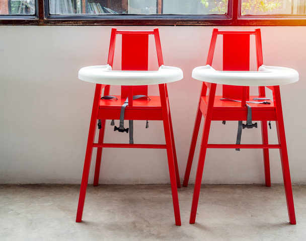 Red high wooden chairs for twin baby for feeding food for children on white wall background near the window. - Photo, Image