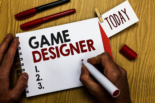 Handwriting text writing Game Designer. Concept meaning Campaigner Pixel Scripting Programmers Consoles 3D Graphics Man holding marker notebook clothespin reminder wooden table cup coffee. - Photo, Image