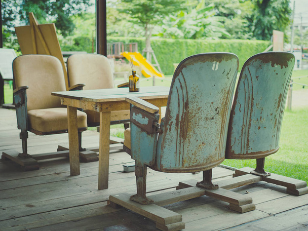 Vintage Színház ülések fából készült asztal, fa padló, a zöld park háttér retro stílusú kávézó. Egyedi keverheted bútor stílus fogalma. - Fotó, kép