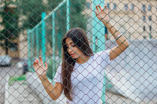 Portrait of a young brunette swag girl behind the rabitz fence. - Fotografie, Obrázek