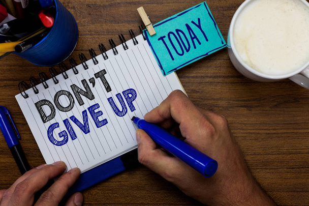 Text sign showing Don t not Give Up. Conceptual photo Determined Persevering Continue to Believe in Yourself Man holding marker notebook clothespin reminder wooden table cup coffee. - Photo, Image