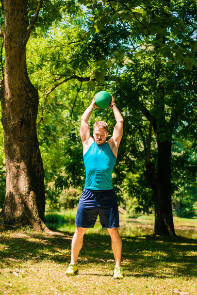 Hombre deportivo haciendo ejercicio con balón medecine en la naturaleza
 - Foto, Imagen