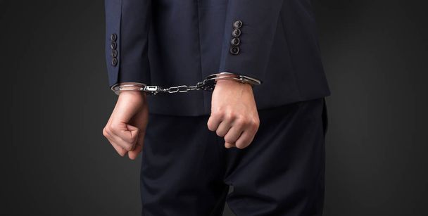 Dark backgrounded close handcuffed man - Valokuva, kuva