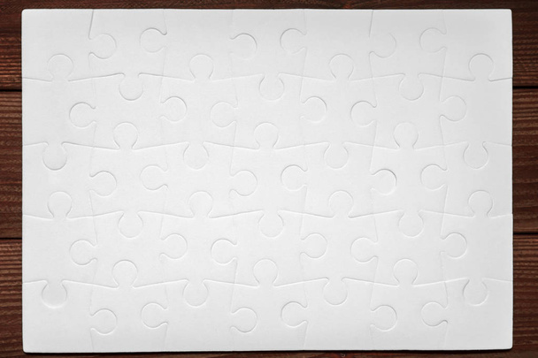 complete white puzzles on wooden table - Foto, Bild