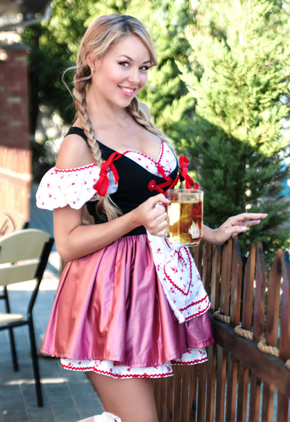 Uśmiechający się blond kobieta z piwem w Octoberfest sukienka.  - Zdjęcie, obraz