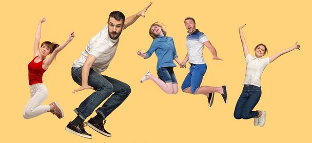 Freedom in moving. young man and women jumping against yellow background - Photo, Image