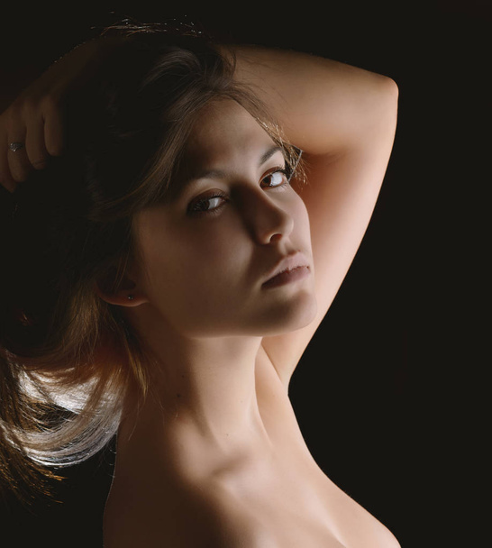Portrait of a beautiful young brunette. Beauty on a black background. - Fotó, kép
