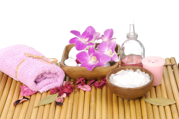 Spa setting with pink towel, salt white orchid in wooden bowl, oil, candle on mat
 - Фото, изображение