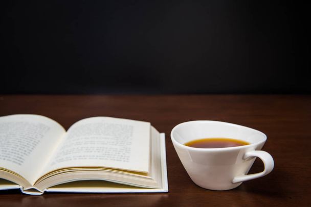 un livre ouvert sur le bureau avec une tasse de café
 - Photo, image