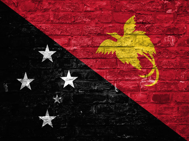 Flag of Papua New Guinea over an old brick wall background, surface - Photo, Image