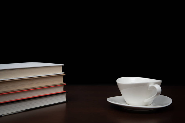 libros apilados en el escritorio con una taza de café
 - Foto, imagen