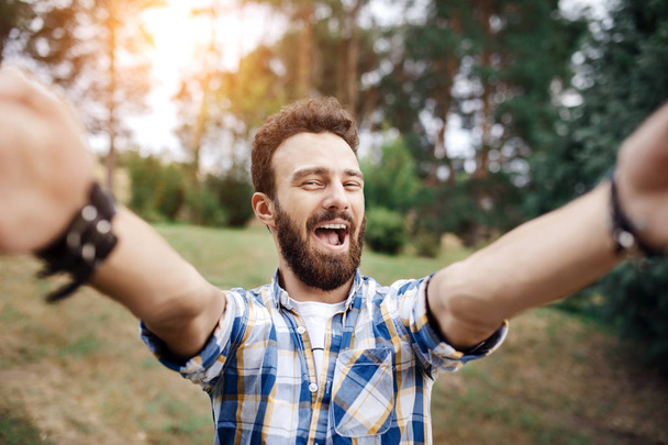 Excited young hipster man make selfie in the park at the sunset. - Foto, Imagem