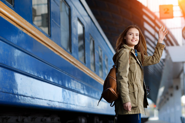 Happy young woman waitng train on the railway station platform. Woman travel with the train. - Φωτογραφία, εικόνα