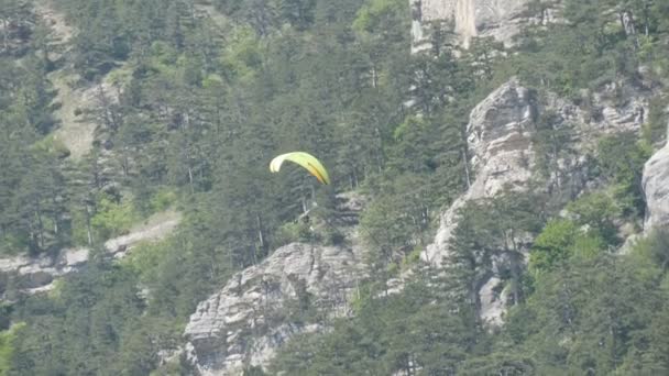 Κίτρινο αλεξίπτωτο να πετά με φόντο πράσινο βραχώδη βουνά της Κριμαίας - Πλάνα, βίντεο
