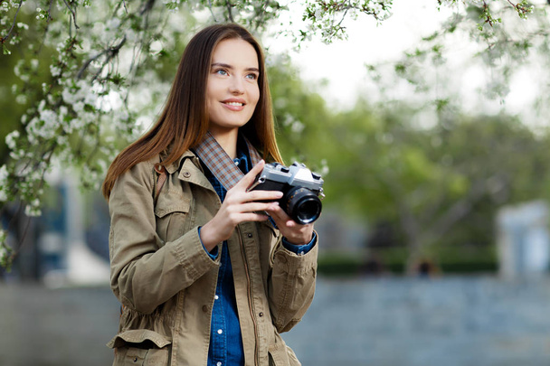 Beautiful young woman using vintage photo camera in the park. - Foto, Imagem