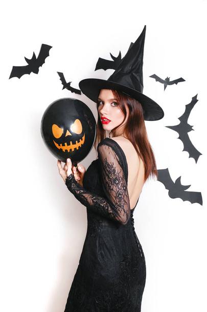 sexy woman in black witch halloween costumes with balloon on party over white background - Foto, afbeelding