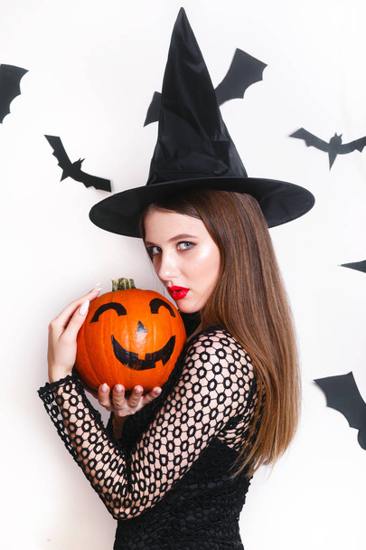 sexy woman in black witch halloween costumes with pumpkin on party over white background - Фото, зображення