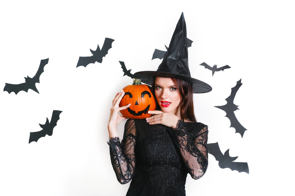 sexy woman in black witch halloween costumes with pumpkin on party over white background - Фото, изображение