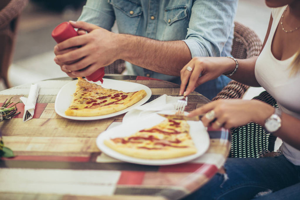 Casal comer pizza lanche ao ar livre, close up. Eles estão compartilhando pizza e comer
. - Foto, Imagem
