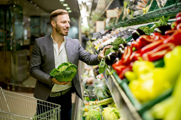 スーパーで野菜を買う若い男 - 写真・画像