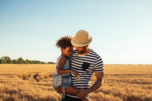 Young african american father and daughter having good time in fields - Foto, Imagen