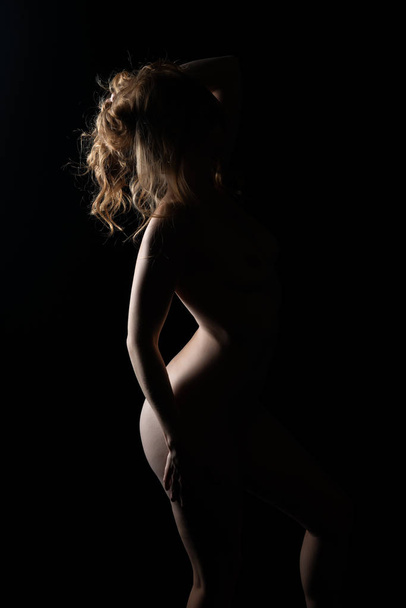 Pretty petite redhead standing nude in deep shadow - Fotoğraf, Görsel