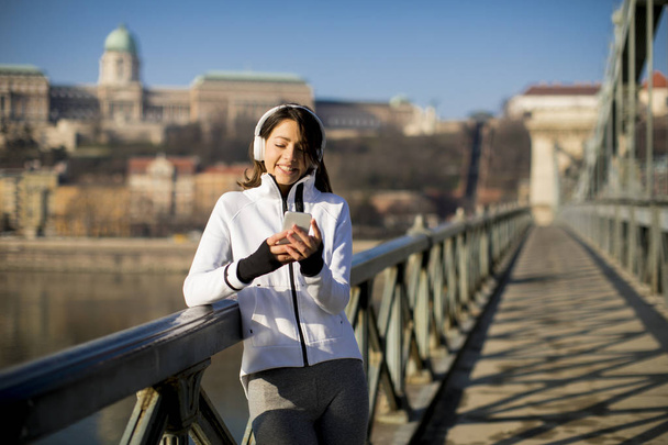 Mujer atleta joven con teléfono móvil en el bridhe en Budapest, Hungría
 - Foto, Imagen