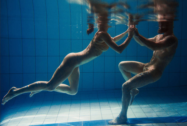 onderwater portret van de atletische, sportieve dansen en het doen van yoga asanas paar (man en vrouw) onder water in het zwembad - Foto, afbeelding