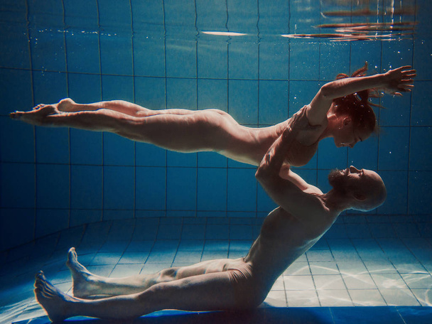 υποβρύχια πορτρέτο του το atlethic, σπορ χορό και κάνοντας γιόγκα asanas ζευγάρι (άνδρας και γυναίκα) υποβρύχια στην πισίνα - Φωτογραφία, εικόνα