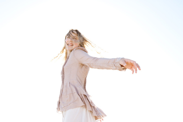 Young girl flicking her wet hair in the air, smiling against the sky. - Foto, Bild
