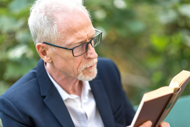 Volwassen man leest een boek buiten - Foto, afbeelding