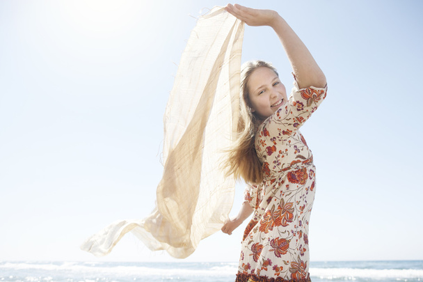 Girl holding a floating sarong in the air, smiling at the camera. - Photo, Image