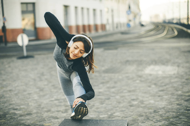 Взгляд на молодую женщину, практикующую растяжку после пробежки на свежем воздухе
 - Фото, изображение