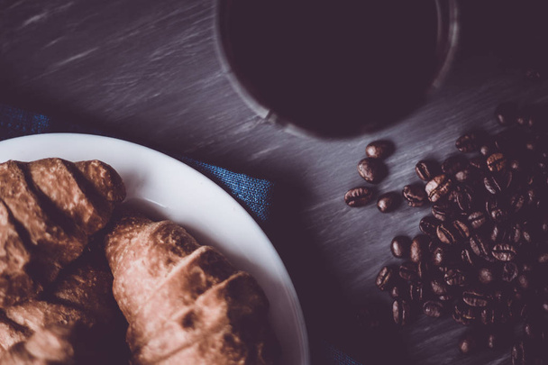 Dessert and coffee beans. Mate moody color. concept of breakfast. Top view. Macro shot of fresh croissants and coffee on a black background. - Zdjęcie, obraz