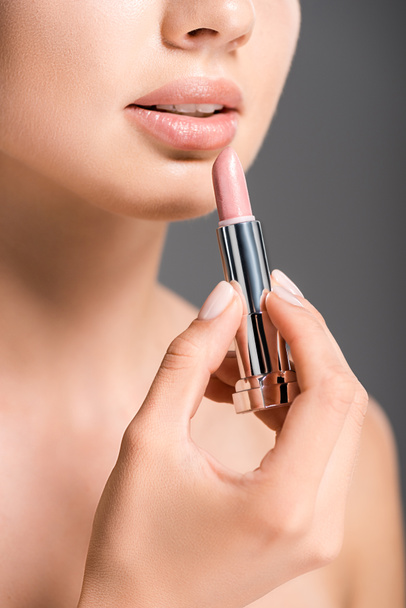cropped shot of woman applying nude lipstick isolated on grey - Фото, изображение