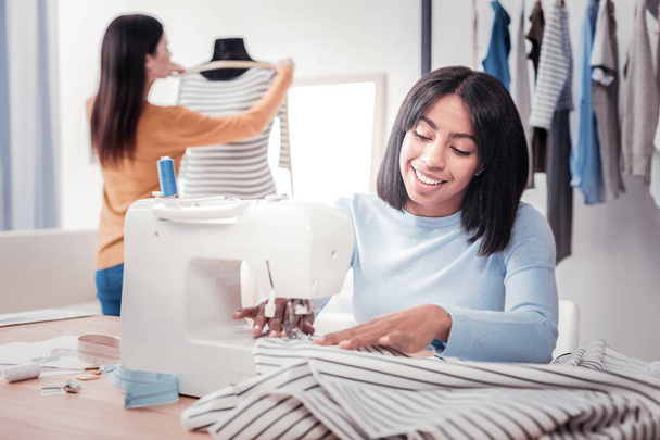 Portrait of positive seamstress sewing a dress - Foto, Imagem