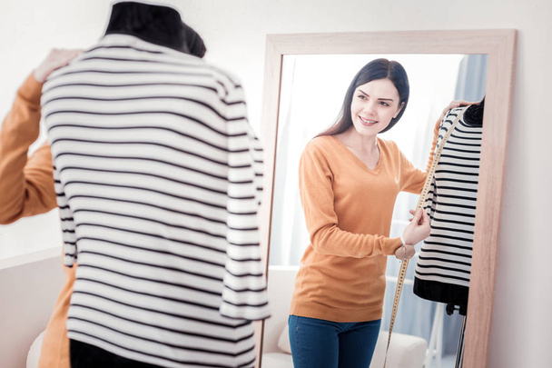 Positive seamstress doing measurements on mannequin - Фото, изображение