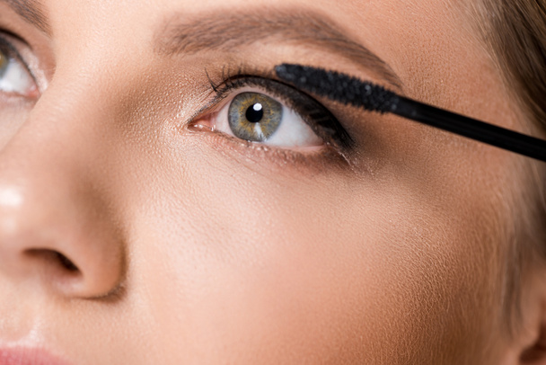 partial view of woman applying black mascara while looking away - Photo, Image