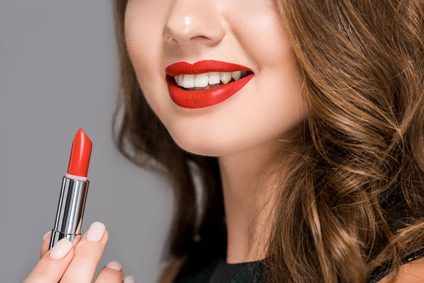 Teilansicht einer lächelnden Frau mit rotem Lippenstift auf grau - Foto, Bild