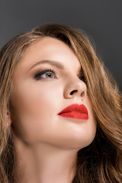 portrait of beautiful woman with red lipstick on lips looking away isolated on grey - Photo, Image