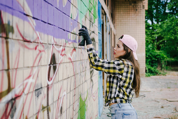 Young woman graffiti artist drawing on the wall, outdoor - Photo, Image