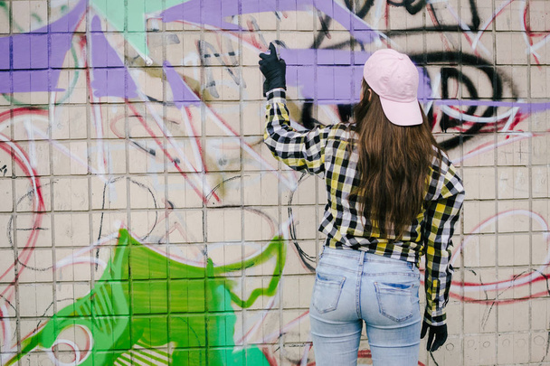 Young woman graffiti artist drawing on the wall, outdoor - Фото, зображення